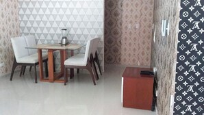 A dining area with a table and chairs, a blender on the table, and a red cabinet.