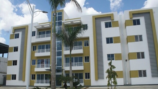 A multi-story building with a modern architectural design, featuring balconies and large windows.