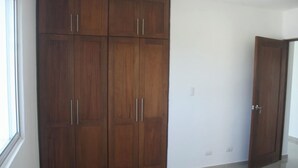 A room with a large wooden wardrobe, a door, and a tiled floor.
