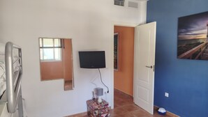 A room with a bed, a television, a small table with a lamp, and a door leading to another room. - Casa Luna ;) ... Semi-detached house a few steps from the sea 🌊 (Cuevas del Almanzora)