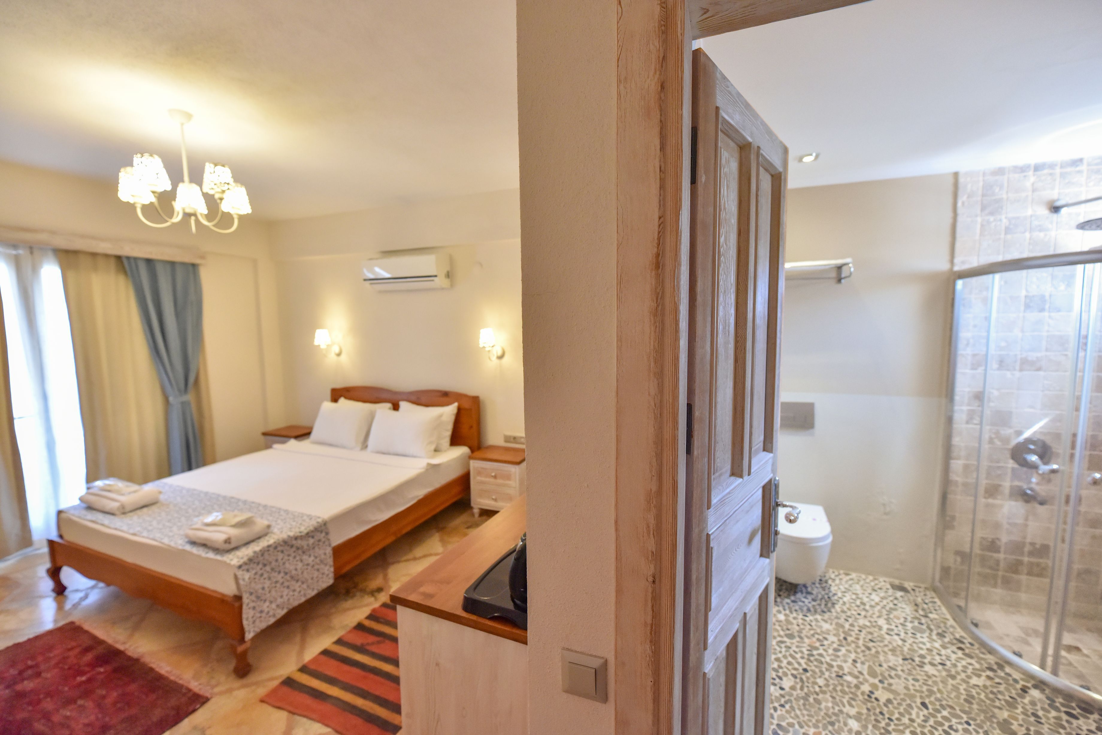 A hotel room with a bed, bedside table, and a shower area.