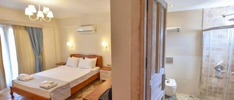 A hotel room with a bed, bedside table, and a shower area.