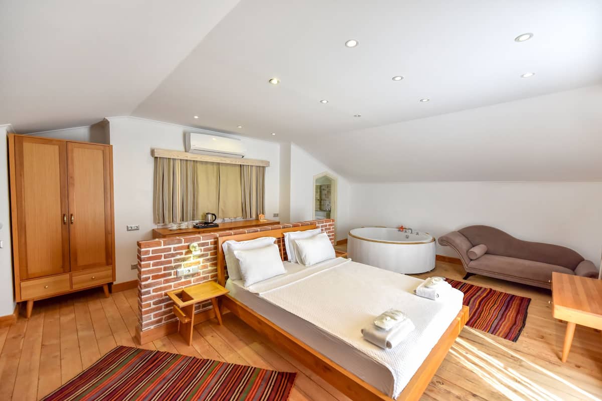 Een slaapkamer met een bed, een houten garderobe, een kleine tafel, een bankje, een sofa en een bad.