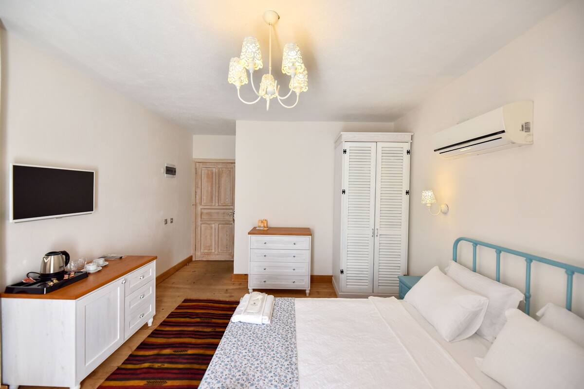 Een slaapkamer met een bed, nachtkastje, garderobe en een aan de muur bevestigde televisie.