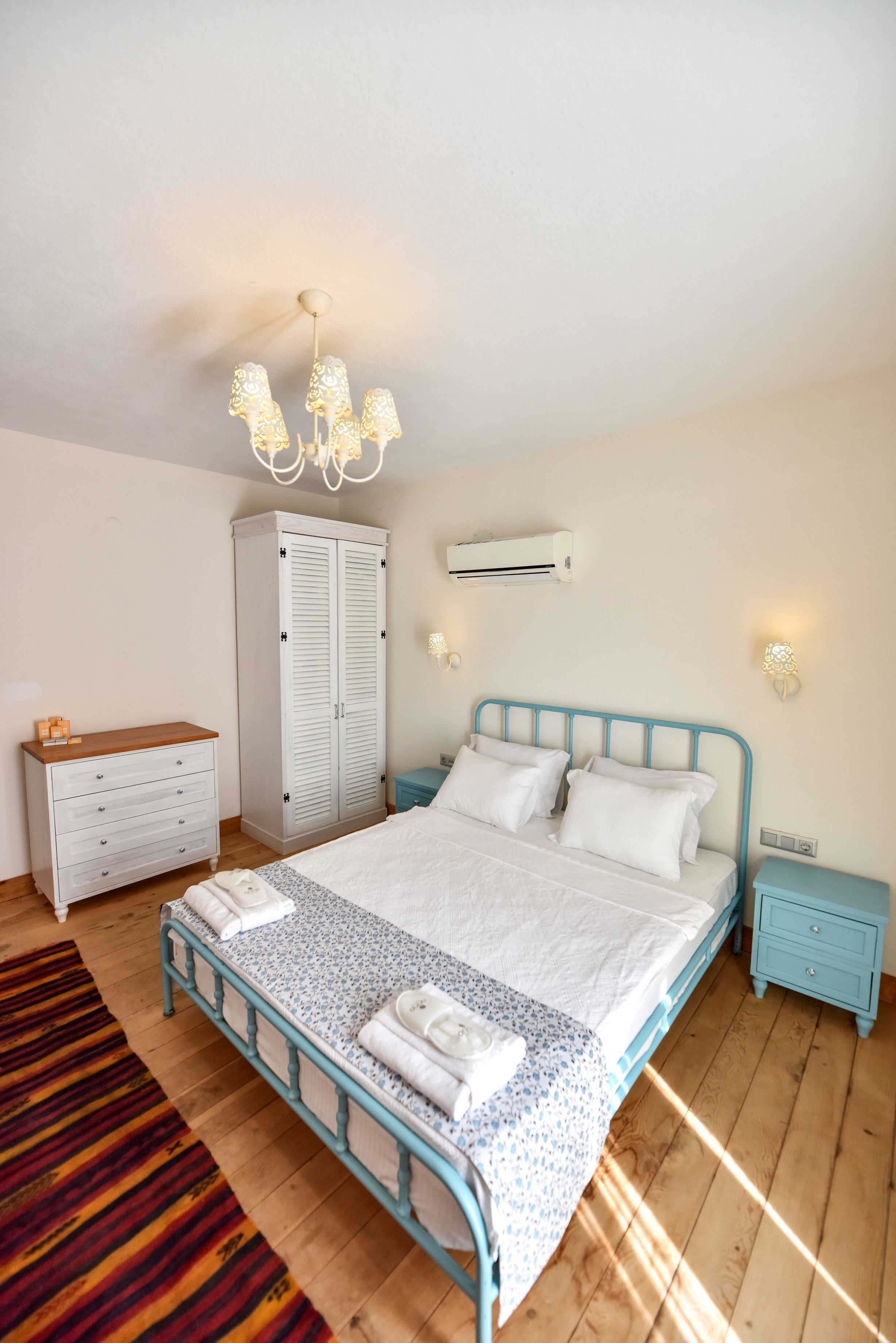 Una camera da letto con un letto, un armadio, un comodino e un tappeto decorato.
