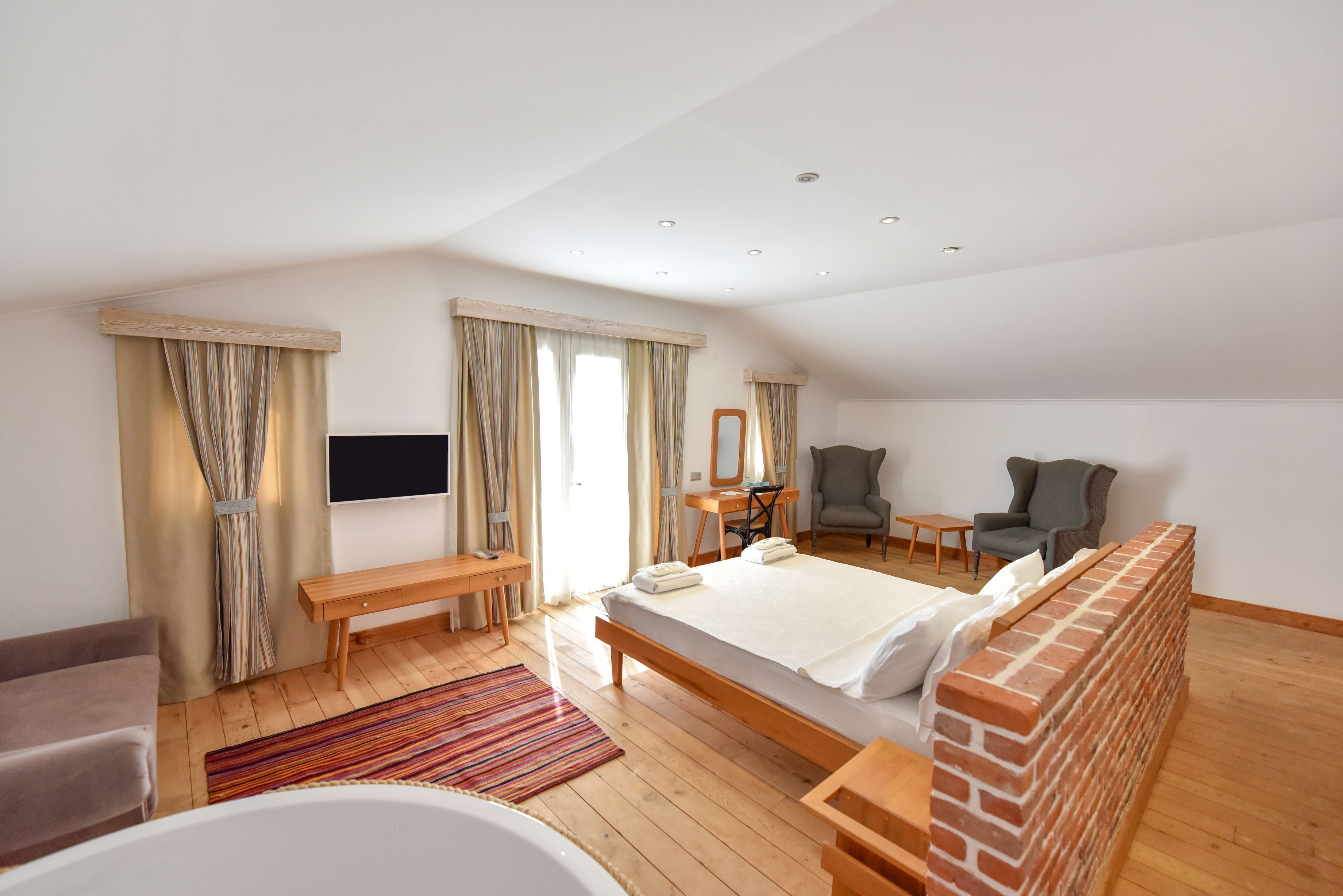 Een moderne hotelkamer met een groot bed, een bureau, een stoel, een televisie en een bakstenen muur.