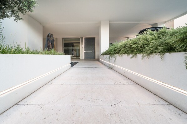 A modern, minimalist corridor with a concrete floor, white walls, and a glass door leading to a room labeled "TORRE BIANCA".