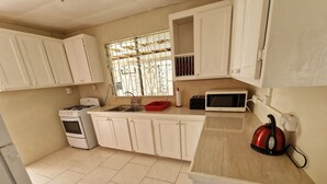 A kitchen with white cabinets, a gas stove, a microwave, and a kettle. - Family-friendly home from home located close to beach, bars and restaurants (Bridgetown)
