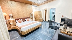 A modern hotel room with a large bed, a desk, and a seating area. - Spree Ashodev Hotel (Bidar)