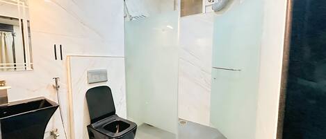 Ein modernes Badezimmer mit einer gläsernen Duschkabine, einer schwarzen Toilette und einem weißen Marmorboden.