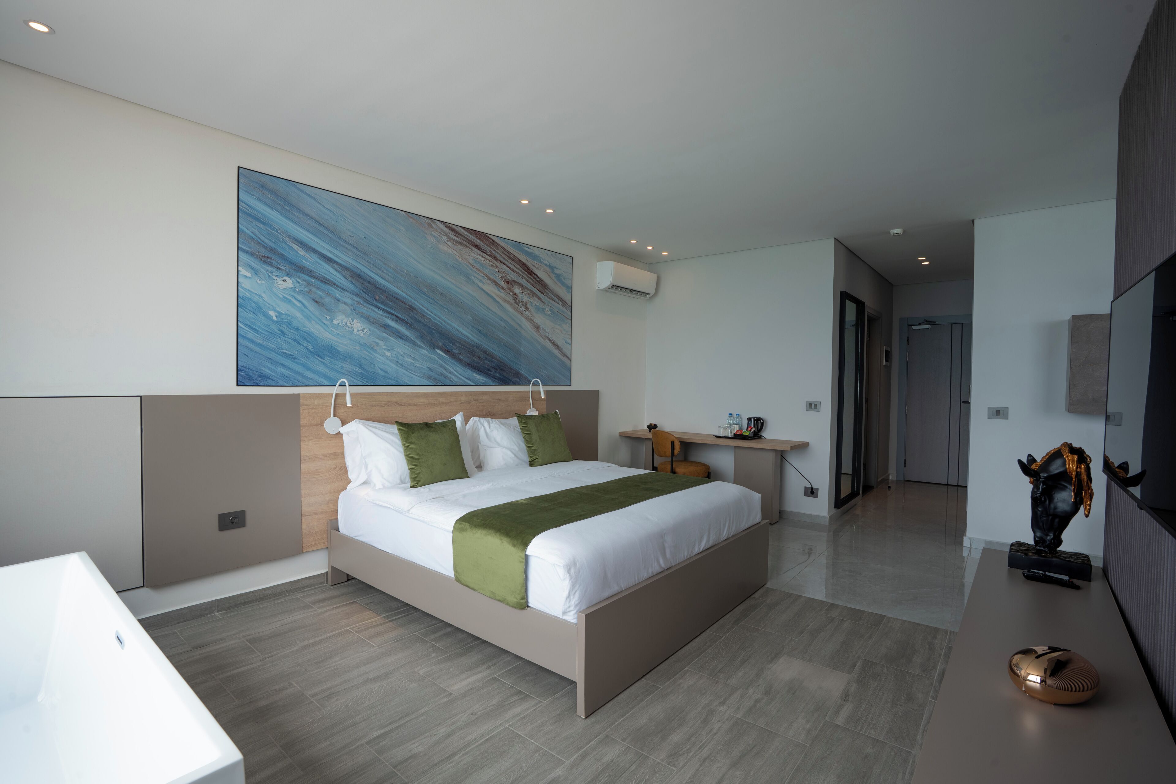 Un dormitorio moderno con una cama grande, un escritorio y un cuadro en la pared.