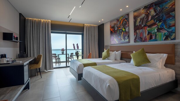 A modern hotel room with two beds, a desk, and a balcony with a view. - Beverly Beach Hotel (Jounieh)