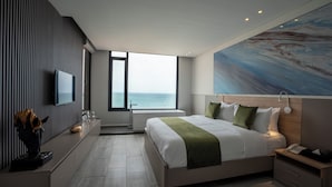 A modern hotel room with a large bed, a view of the sea, a flat-screen TV, and a painting on the wall. - Beverly Beach Hotel (Jounieh)
