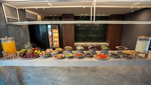 A buffet setup with various food items and a fruit punch dispenser. - Beverly Beach Hotel (Jounieh)