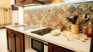 Una cocina con diseño moderno, que incluye un lavamanos de acero inoxidable, un microondas y una variedad de utensilios de cocina sobre la encimera.