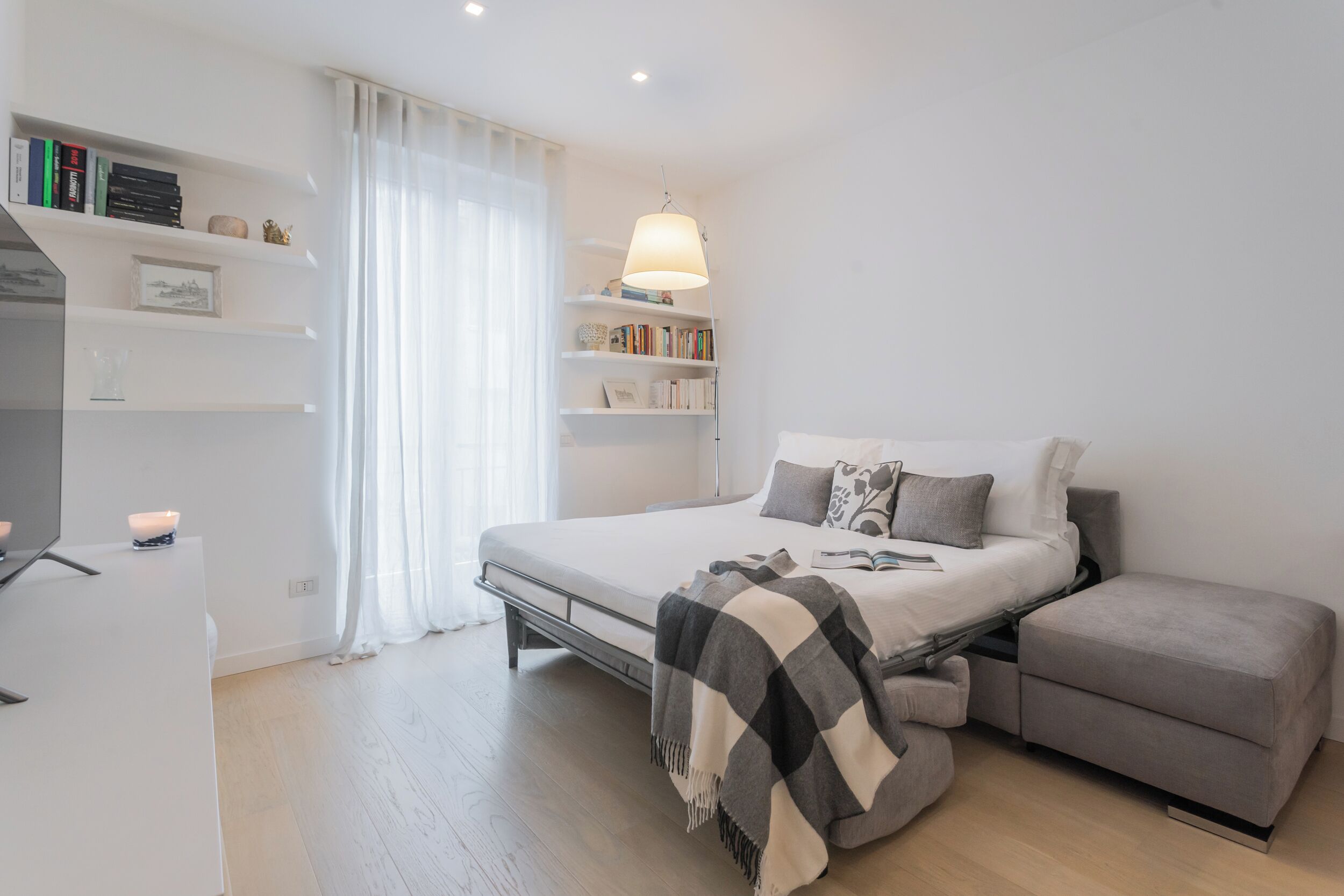 Une chambre à coucher moderne avec un lit, des tables de chevet, un bureau et une bibliothèque.