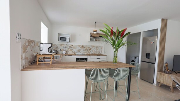 A modern kitchen with a wooden island, bar stools, a microwave, and a refrigerator.