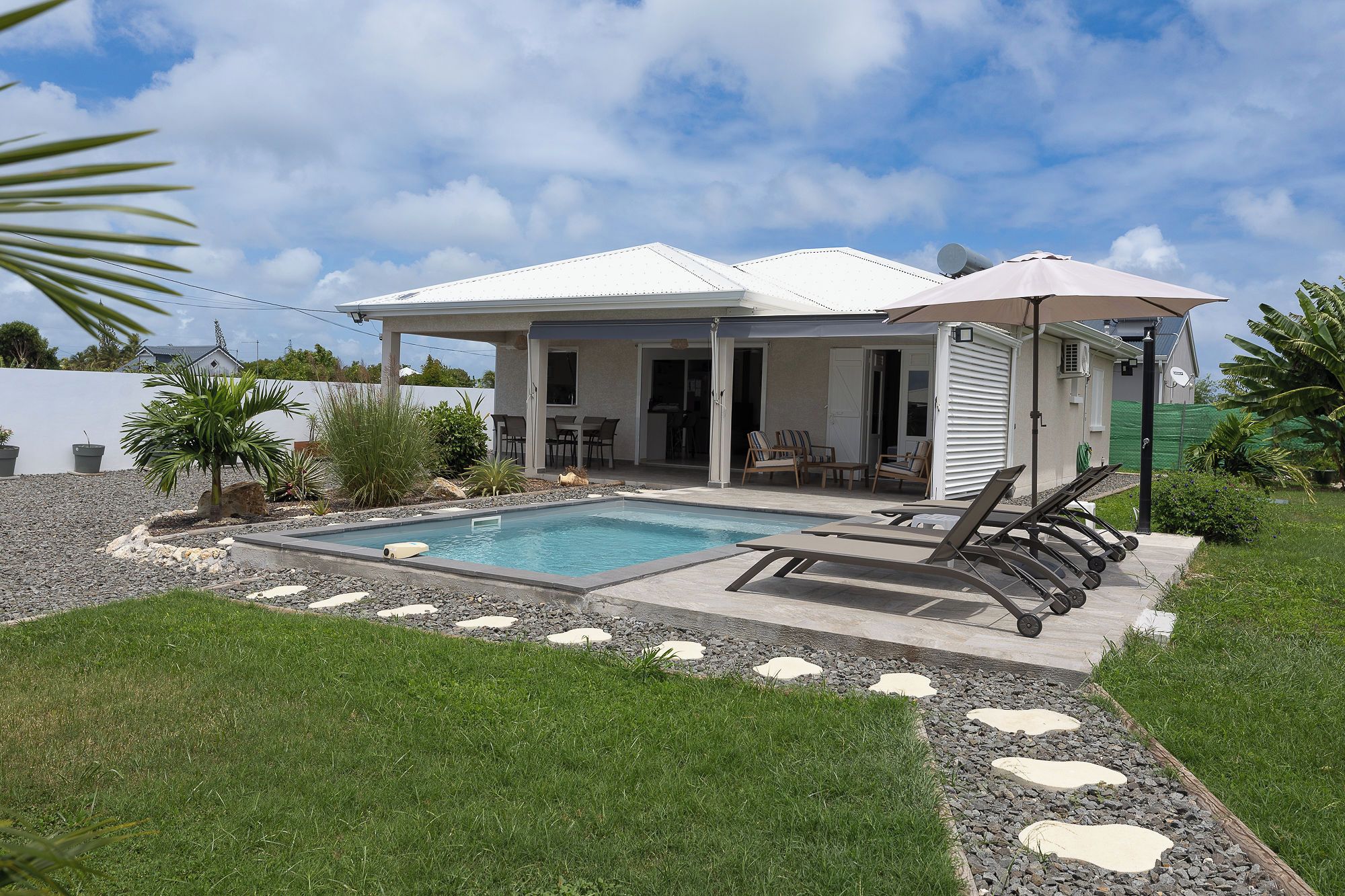A residential property with a swimming pool, outdoor seating, and a covered patio.