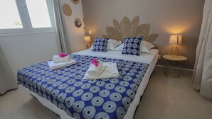 A hotel room with a bed, two bedside lamps, a wall with decorative plates, and a window with curtains.
