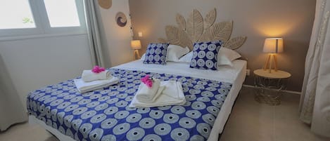Une chambre d’hôtel avec un lit, deux lampes de chevet, un mur décoré d’assiettes et une fenêtre avec des rideaux.