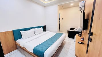 Una habitación de hotel moderna con una cama, un cabecero de madera, una mesita de noche, un televisor y un ventilador de techo.