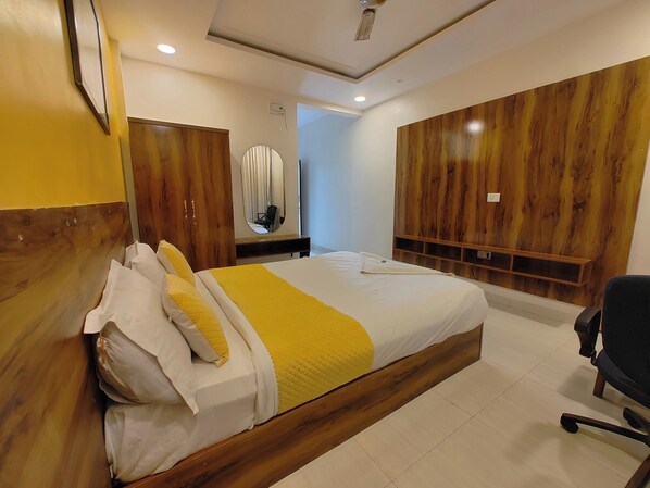 Une chambre d’hôtel avec un lit en bois, un bureau avec une chaise, un miroir et une armoire.