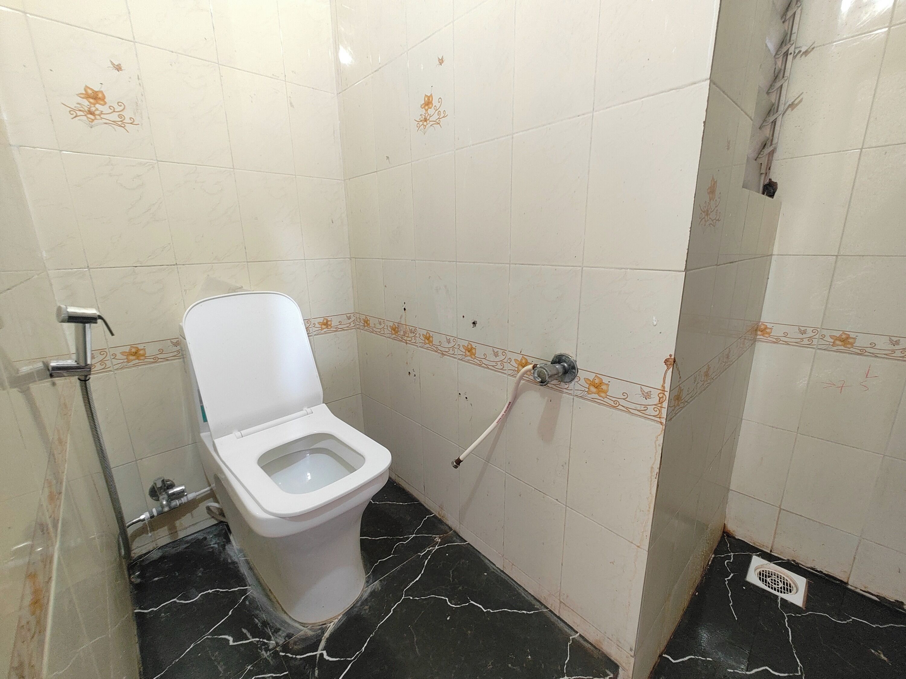 A small bathroom with a toilet, a shower, and a drain.