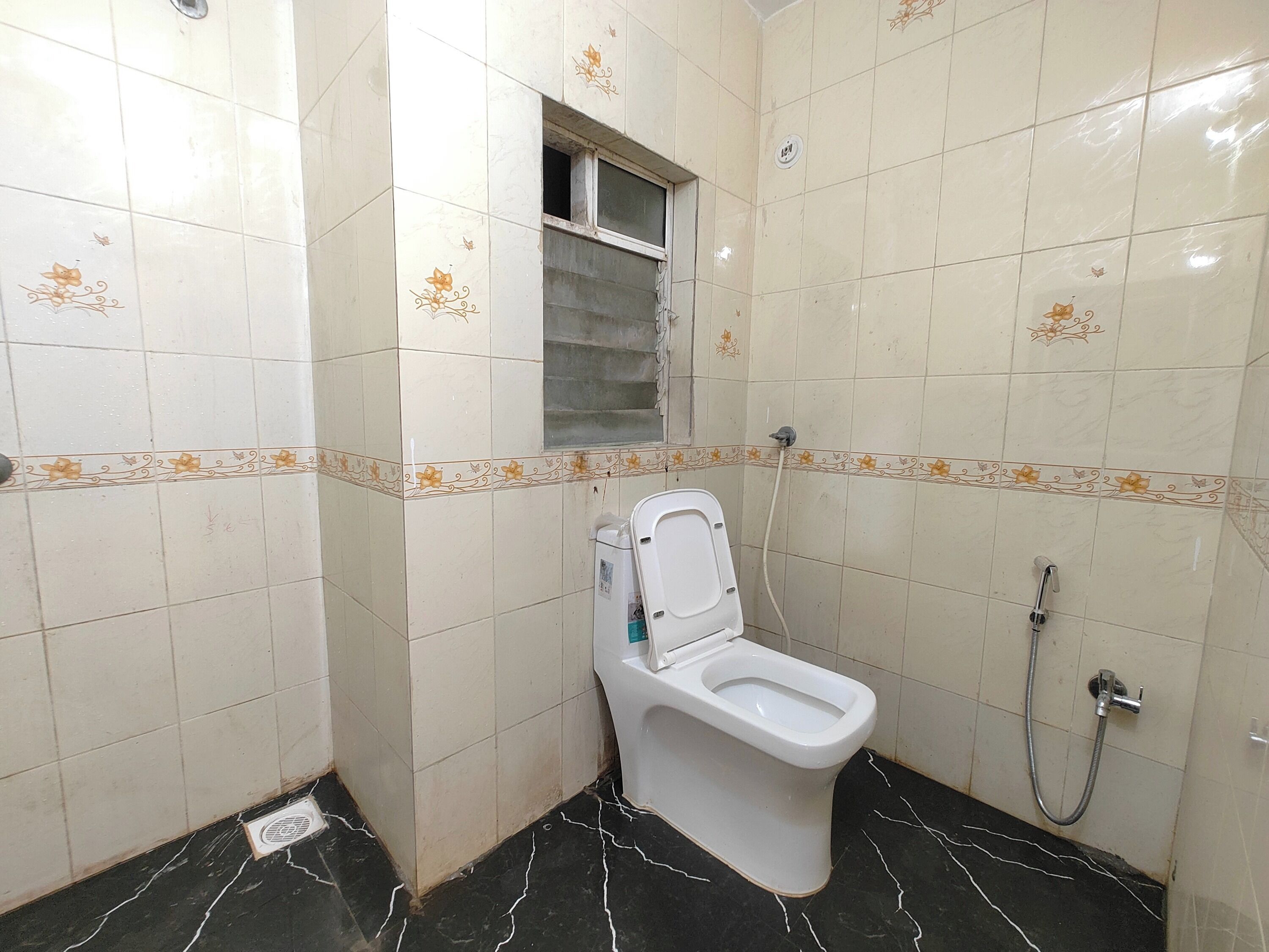 A small bathroom with a toilet, a shower, and a window.