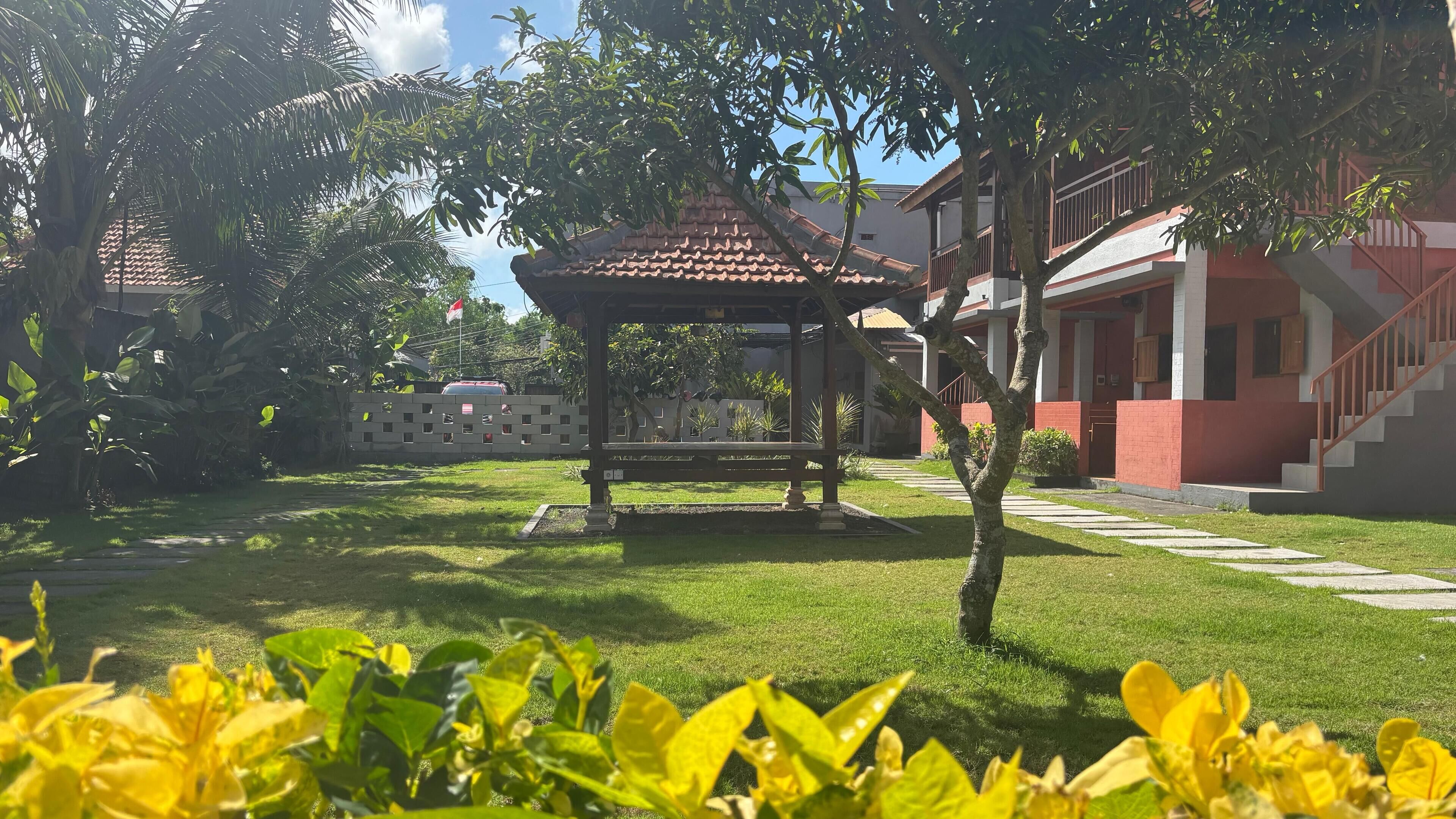 A gazebo in a well-maintained garden with a clear sky.
