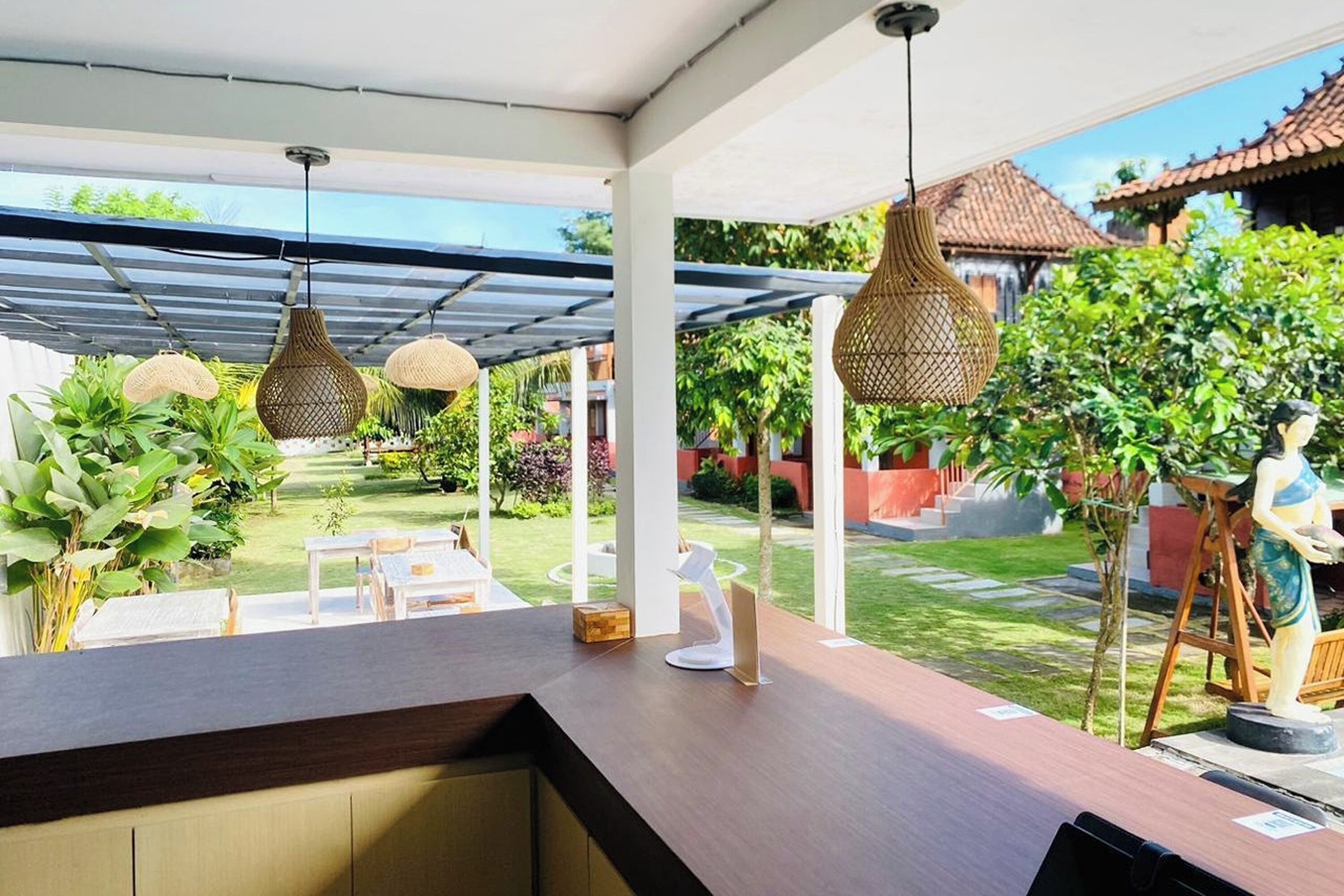 Un área de estar al aire libre con una mesa y sillas de madera, rodeada de follaje y arquitectura tradicional.