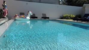 Une piscine aux eaux cristallines, dotée de chaises longues et ornée d’une statue.