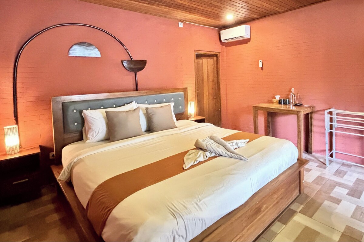 A neatly made bed with a striped bedspread, a bedside lamp, and a wooden headboard.