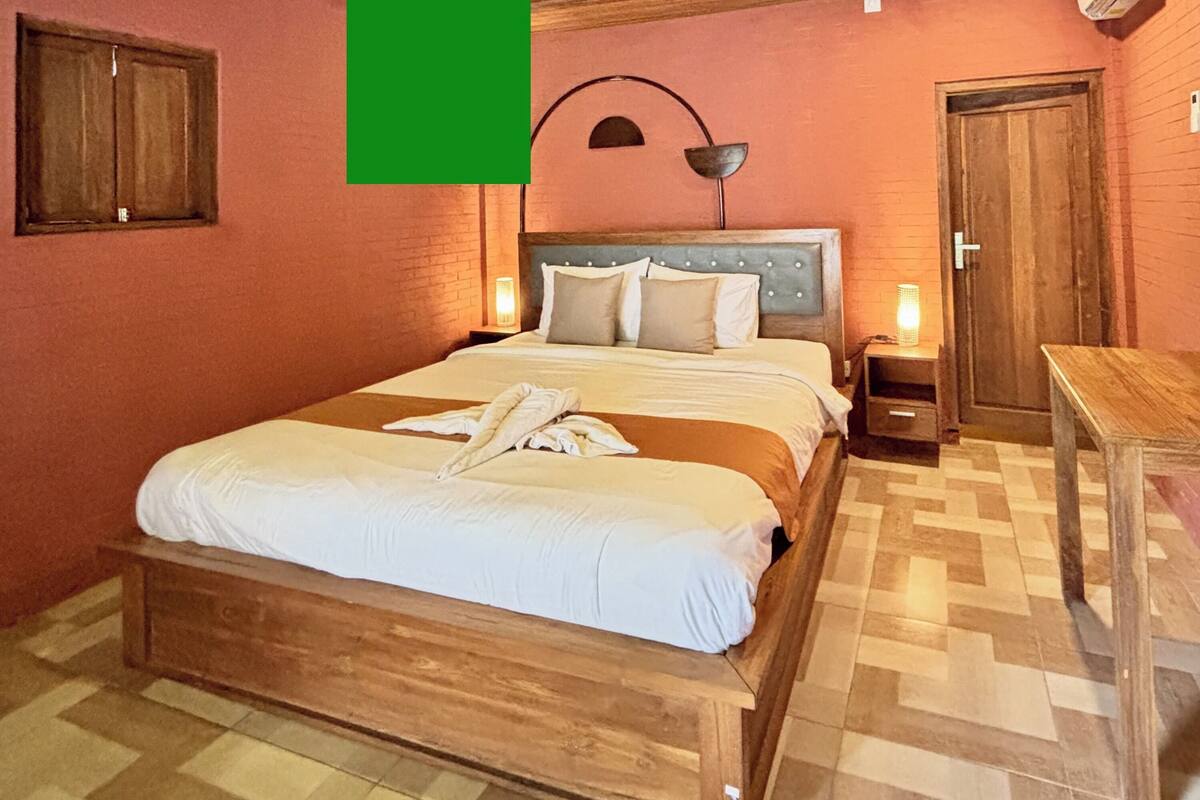 Une chambre à coucher avec un lit en bois, une table de chevet, une lampe et une porte.