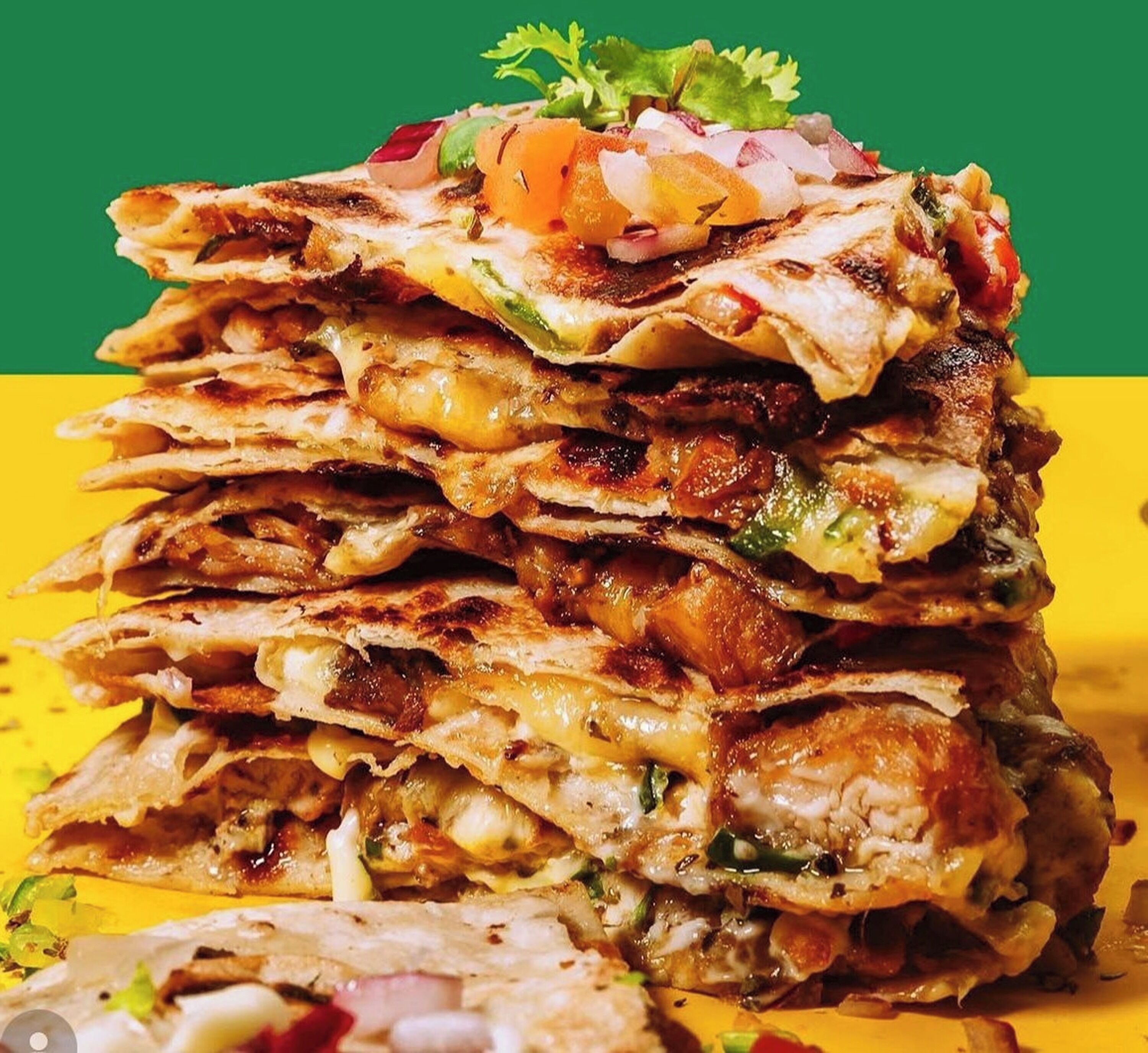 Una pila de quesadillas con queso derretido y cobertura.