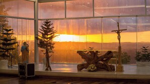A room with large windows, a wooden sculpture, and a small Christmas tree. - Amaya View (Cagayan de Oro)