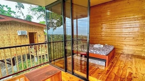 A wooden cabin with a glass balcony, a bed, and a small table. - Amaya View (Cagayan de Oro)
