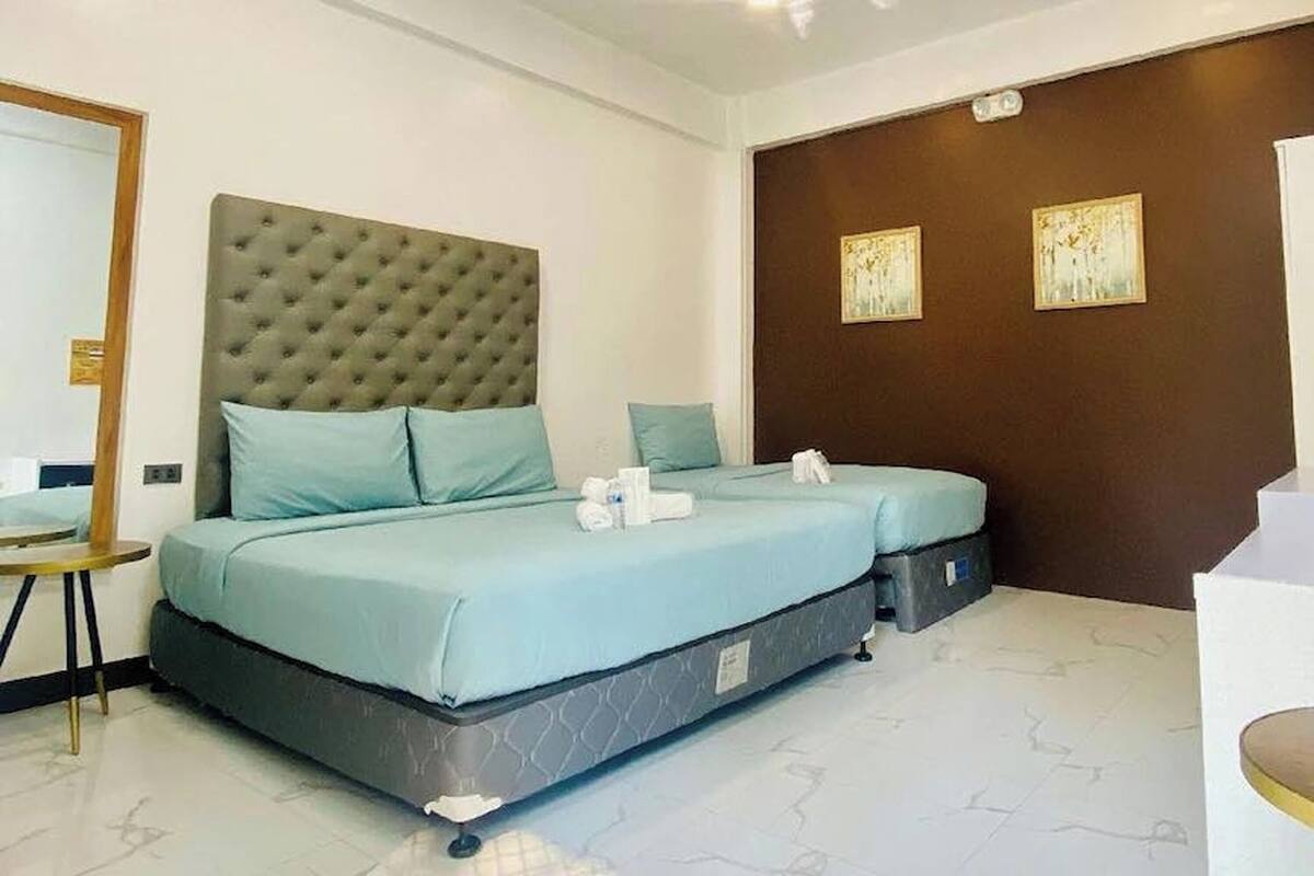 A hotel room with a large bed, a bedside table, and two wall-mounted artworks.