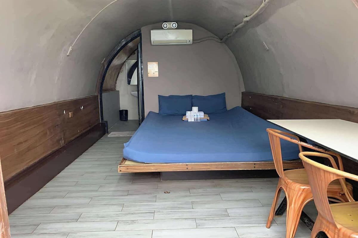 A compact room with a bed, a small table, and a chair.