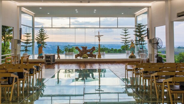 A spacious interior with a reflective floor, large windows offering a view of the outdoors, and wooden chairs arranged for seating. - Amaya View (Cagayan de Oro)