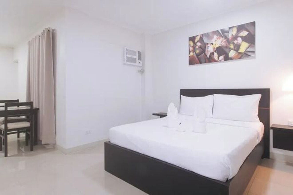 A hotel room with a large bed, a desk, and a chair.