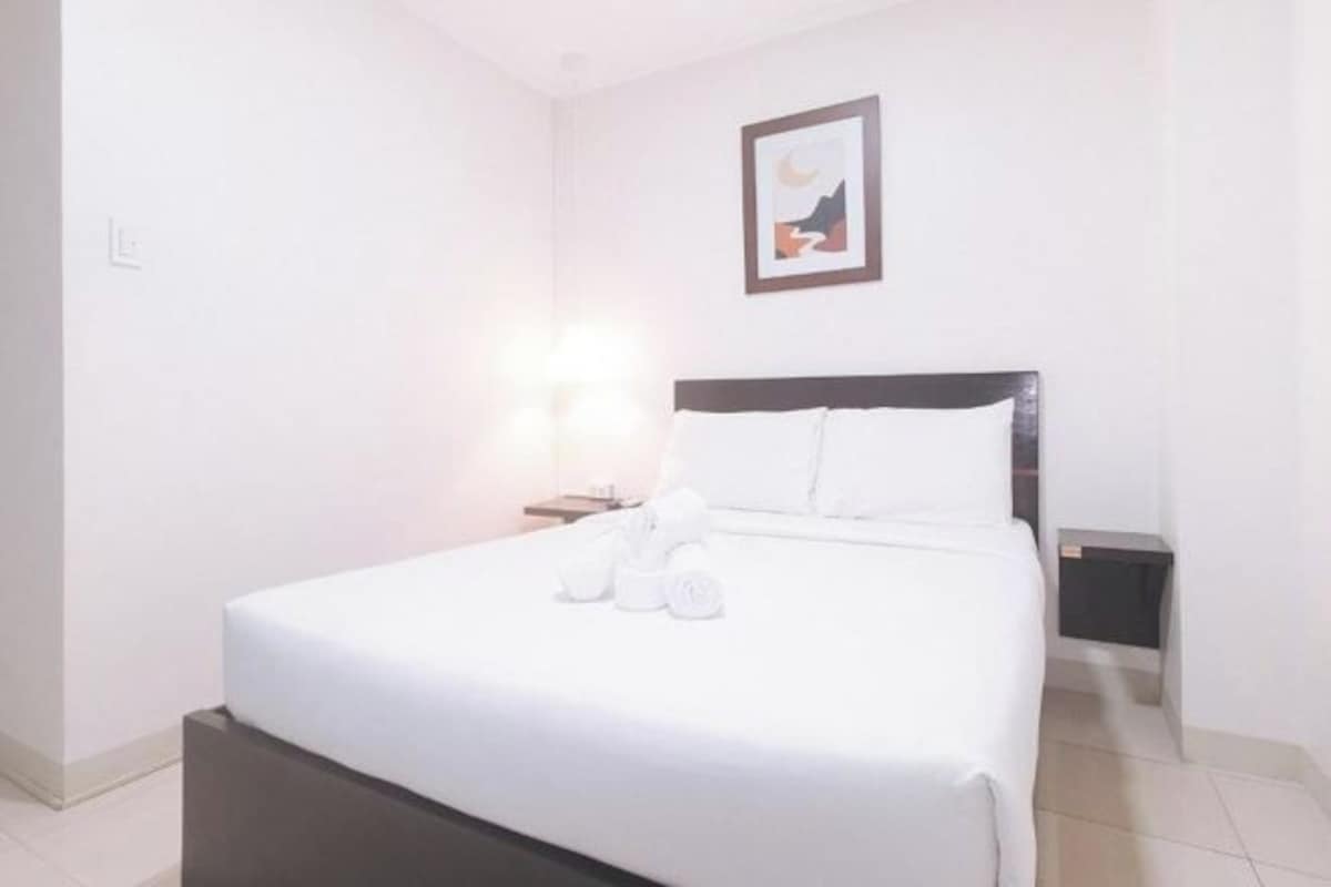 A hotel room with a bed, a nightstand, and a wall-mounted picture.