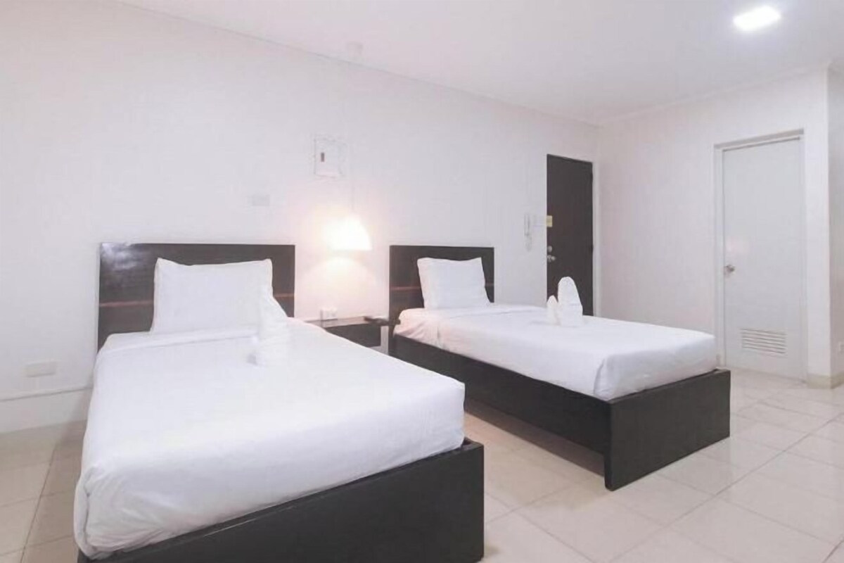A hotel room with two beds, each with a black headboard and white bedding.