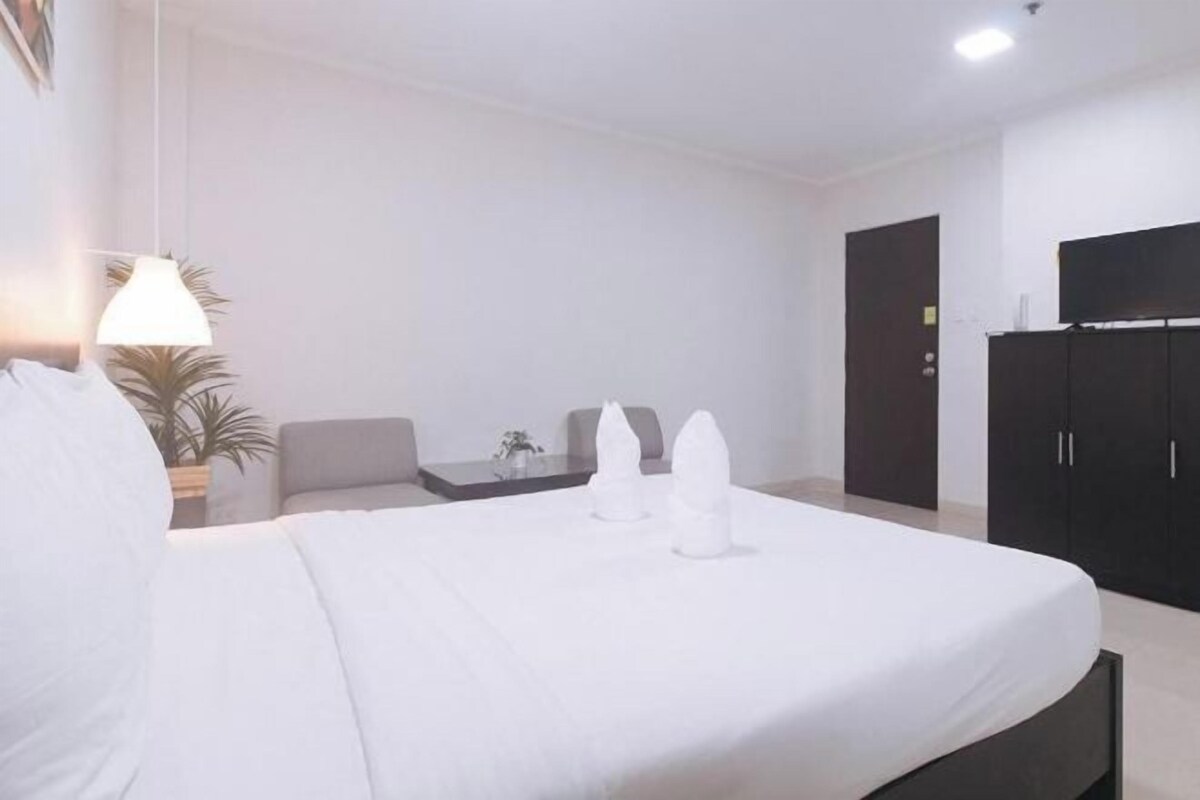 A hotel room with a bed, a desk, a chair, a TV, and a wardrobe.