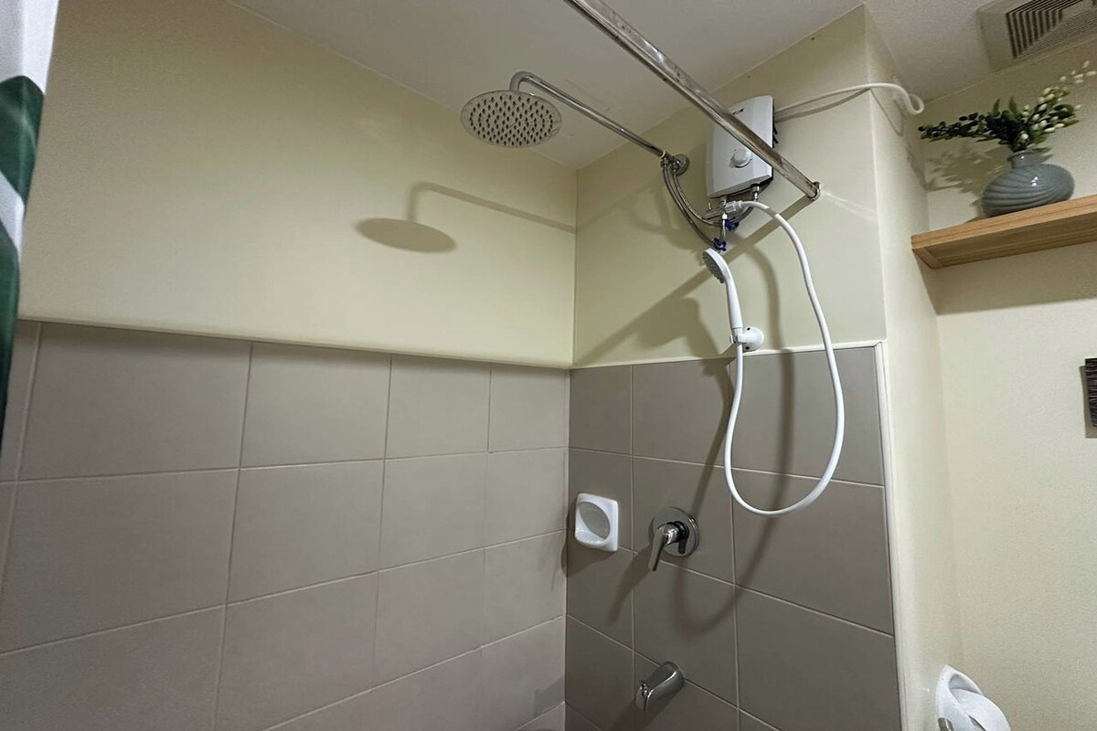 Une salle de bain avec une douche, un porte-serviettes et une étagère sur laquelle est posé un vase.