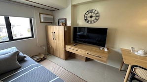 A modern living room with a sofa, TV, wooden cabinet, and a small dining table. - Avida Units Staycation near Ayala Serin Tagaytay (Tagaytay)