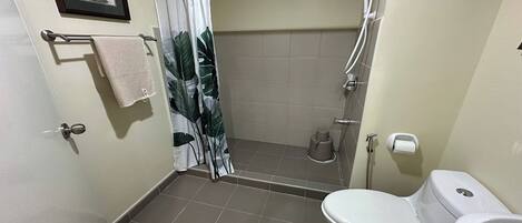 A bathroom with a shower, toilet, and a towel rack.