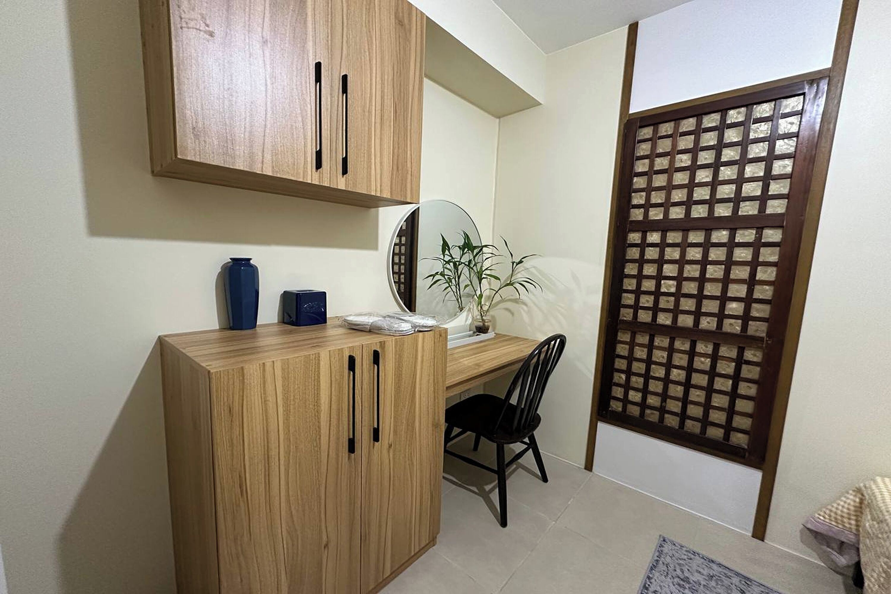 A compact room with a wooden desk, a chair, a potted plant, and a traditional sliding door.