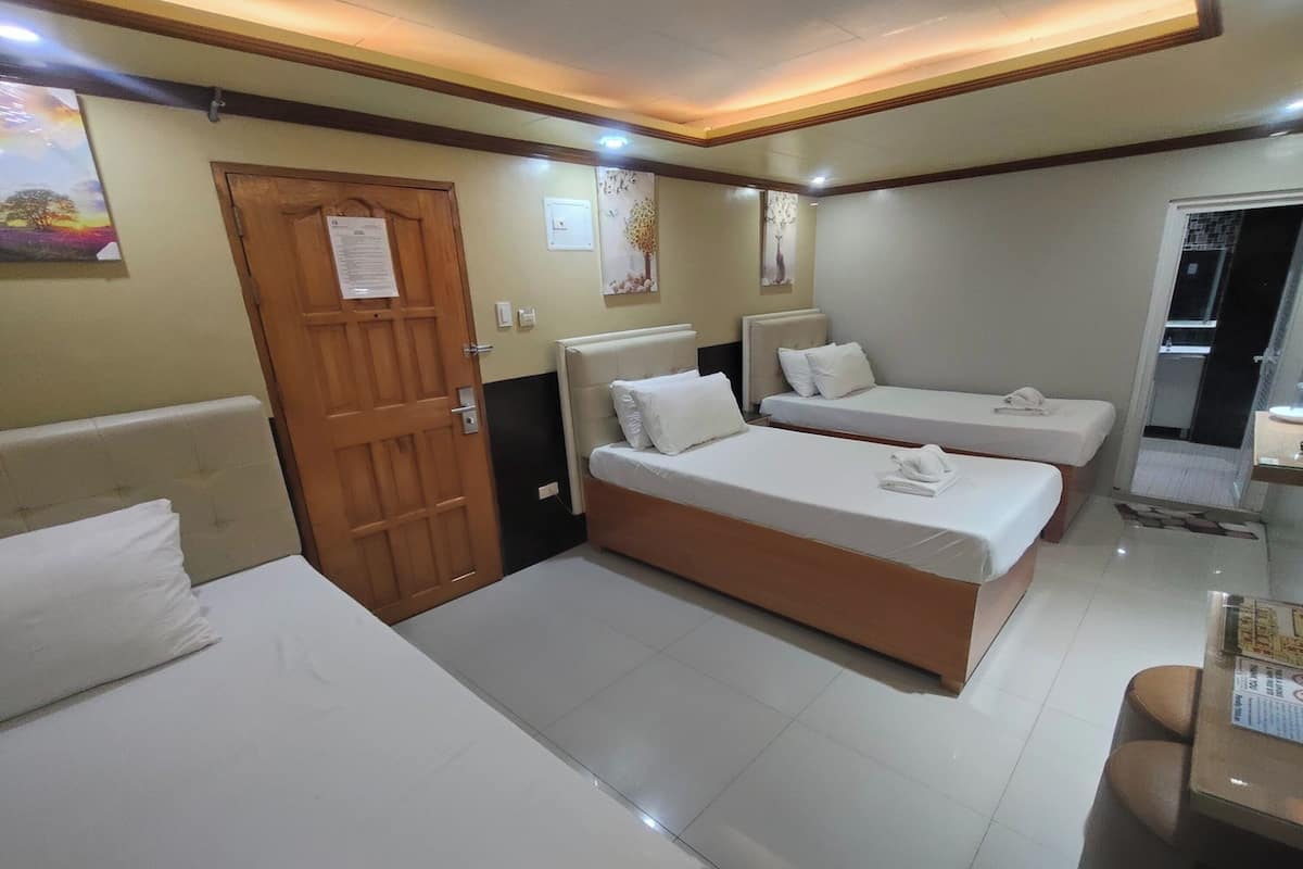 Une chambre d’hôtel avec deux lits, une porte en bois et une petite table sur laquelle se trouve un menu.