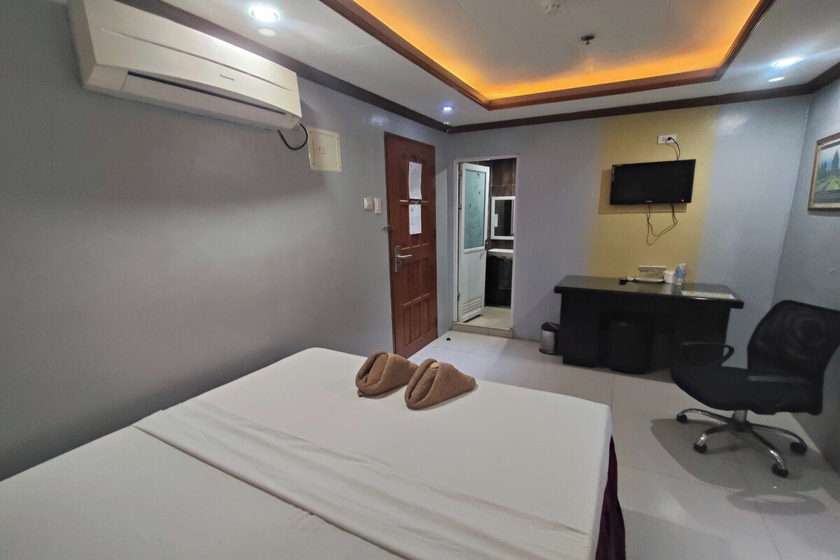 Une chambre d’hôtel équipée d’un lit, d’un bureau, d’une chaise, d’une télévision et d ’un appareil de climatisation.