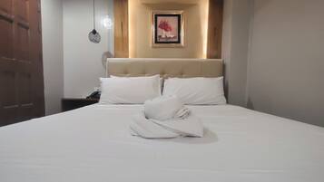 A neatly made bed with white linens and a folded towel in the center.